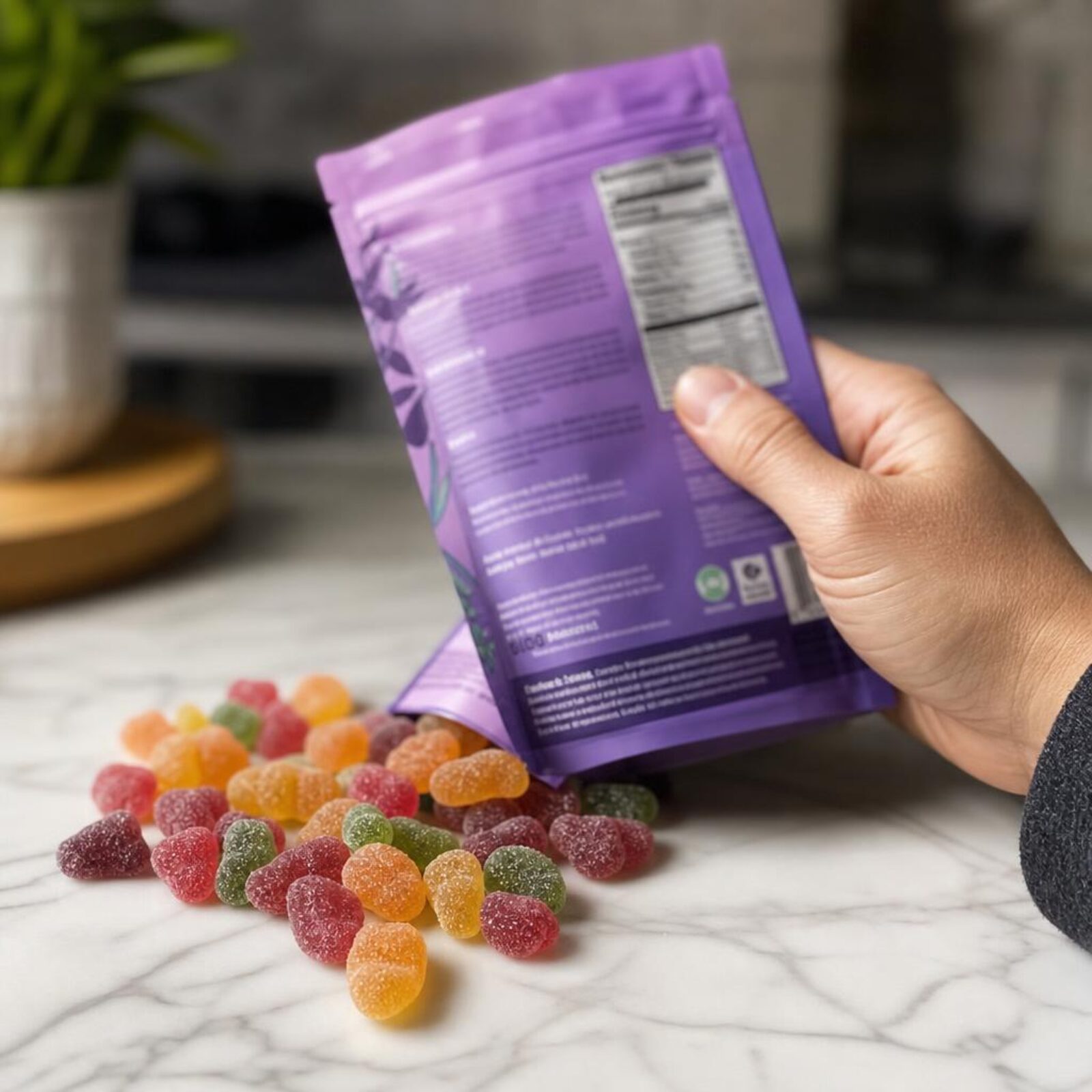 Colorful gummies spilling from a pouch while a hand holds the package label.