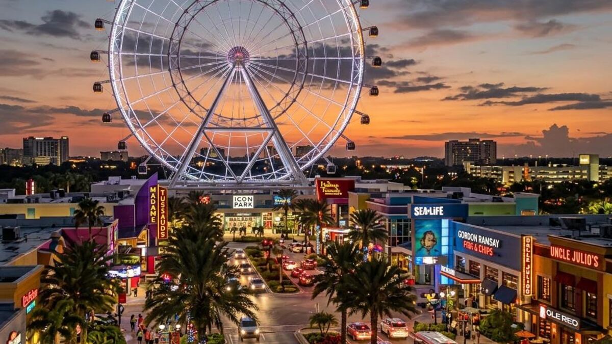Large white observation wheel rising over the International Drive entertainment district at dusk.