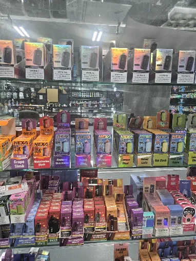 Display case and shelves of disposable vapes in many flavors at 247 Smoke Shop